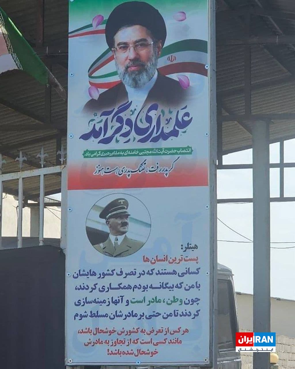 @ايران اينترنشنال: تصویر رسیده به ایراناینترنشنال، پوستر حکومتی نصبشده در یکی از شهرهای ایران را نشان میدهد که روی آن تصویری از مجتبی خامنهای و نقلقولی جعلی و دروغین از هیتلر آمده است.